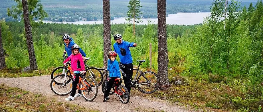 En cyklande familj har stannat på en utsiktsplats i skogen. Foto: Ulf Palm