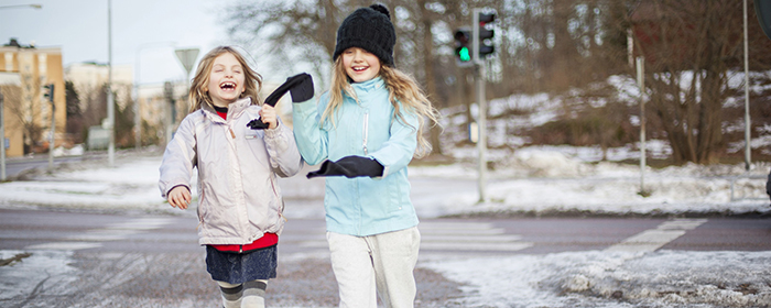 Två glada barn korsar en gata. Det är vinter.