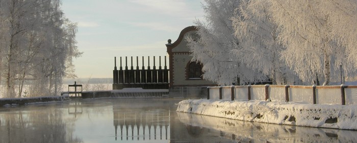 VInterbild över Vattenkraftverket vid Masugn med stilla vatten och frostbeklädda träd runt om
