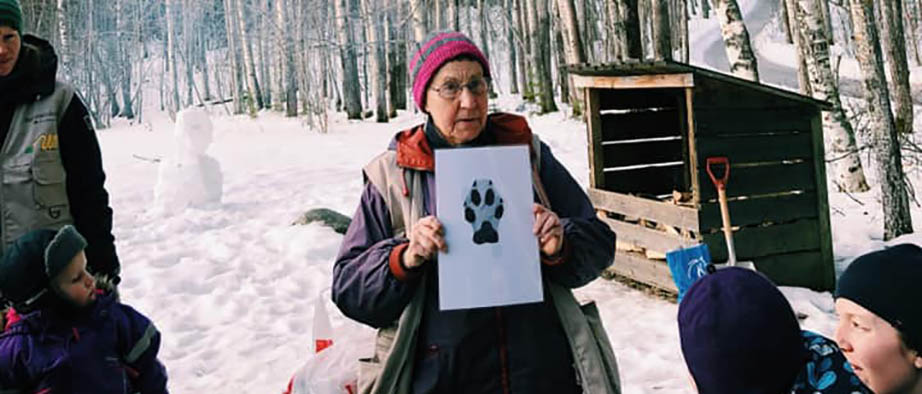 En kvinna i mössa visar upp en bild på ett avtryck av en tass. Vinter.