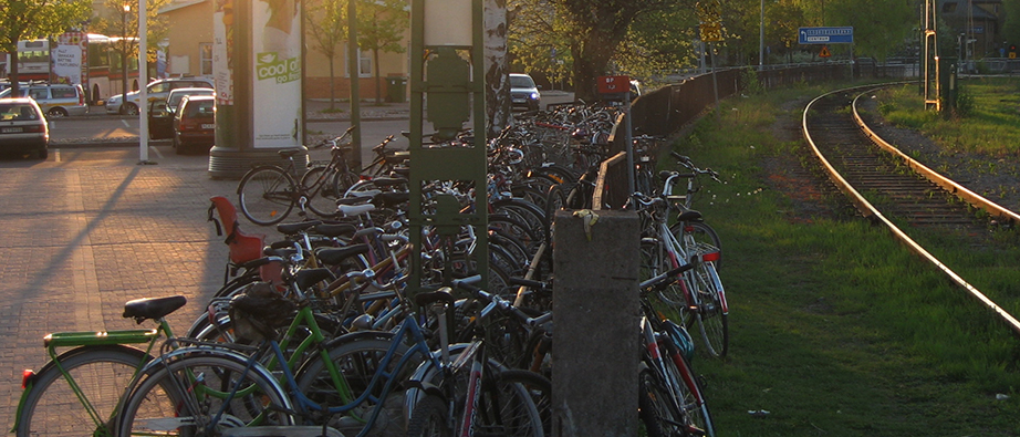 Flera cyklar som står vid ett cykelställ på kvällen
