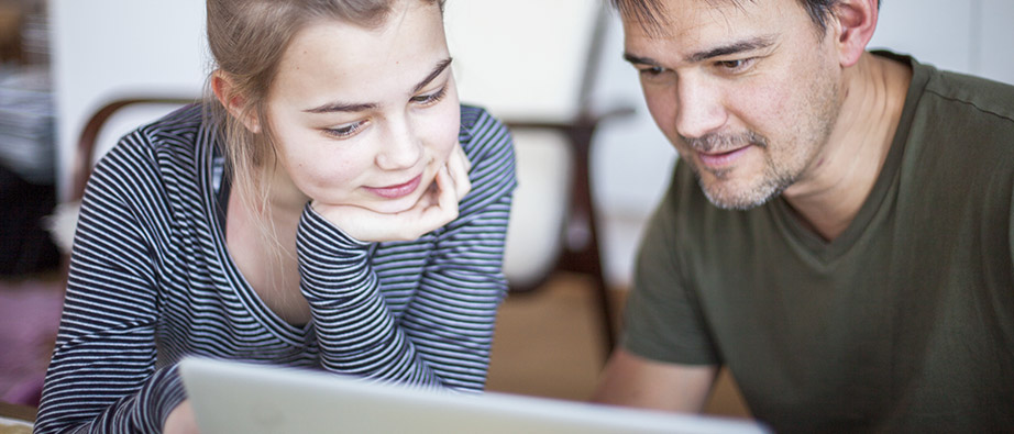 Pappa och dotter tittar engagerat på en datorskärm