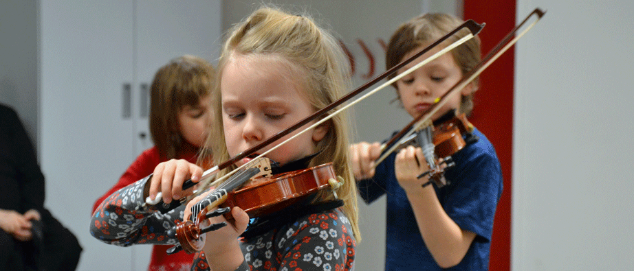 Tre yngre barn spelar fiol