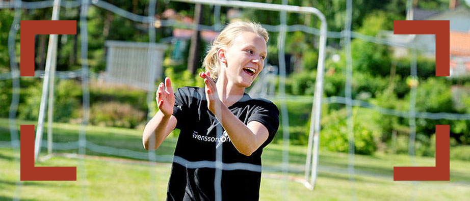 Flicka som skrattar håller i nätet i ett fotbollsmål