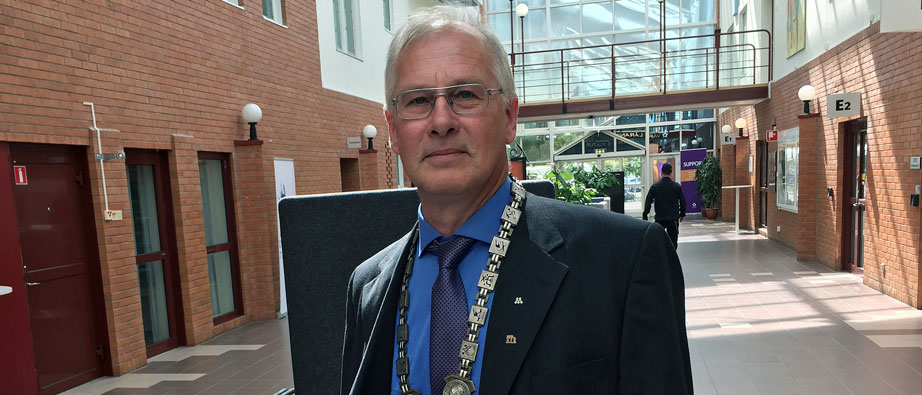 Göran Forsén med den speciella borgmästarkedjan runt sin hals stående i en korridor.