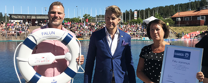 Falun har fått utmärkelsen vattensäker kommun. Representanter från kommunen och Svenska Livräddningssällskapet framför utomhusbassängen på Lugnet.