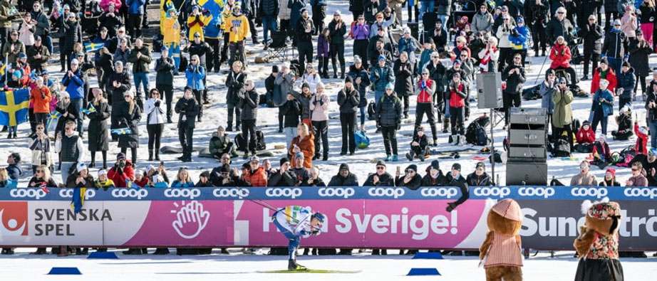 Svensk skidåkare åker framför stort publikhav på Lugnet.