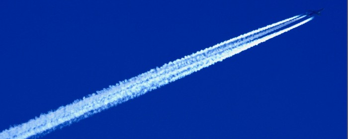 Flygplan stiger upp i den blå skyn och lämnar ett vitt stråk efter sig