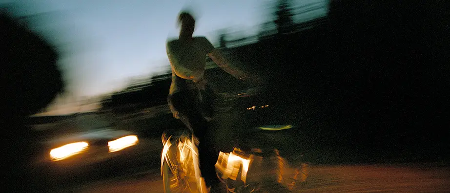 En cyklist kommer åkande i mörkret, endast svaga lampor lyser upp personen