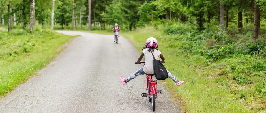 Barn som cyklar i skogsmiljö.