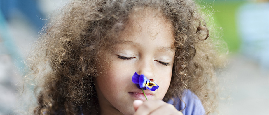 Barn som luktar på en blomma