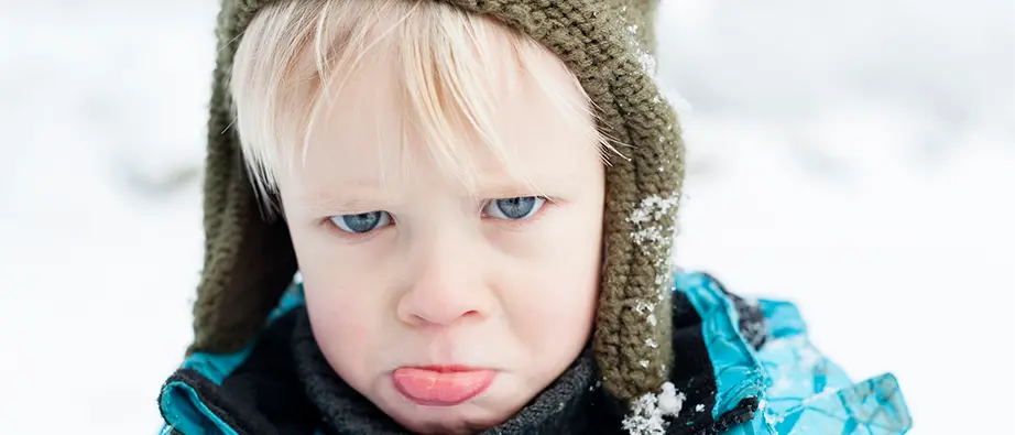 Ett barn som står ute i snön och sträcker ut tungan