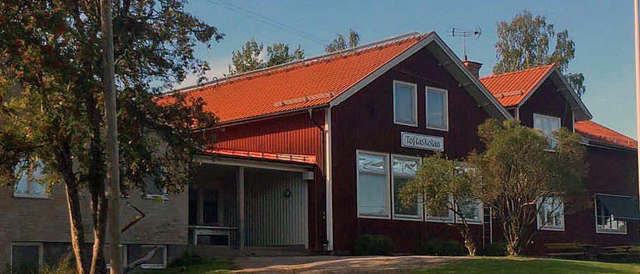 Bild på rödmålad skola med röda takpannor.