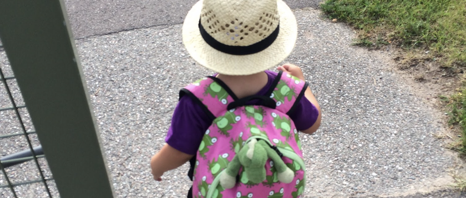Ett litet barn med hatt och ryggsäck