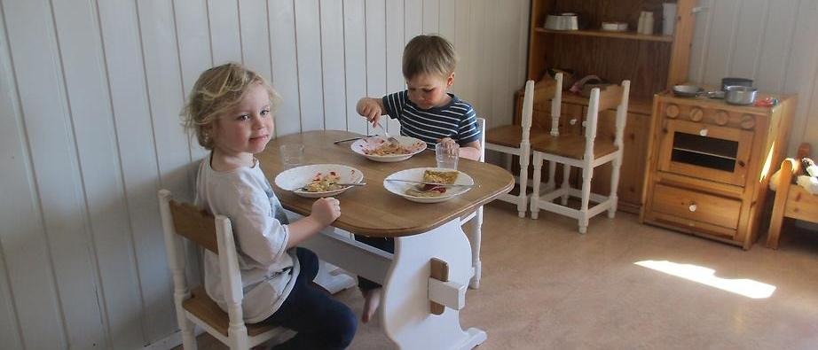 Två barn som sitter vid ett litet bord och äter mat