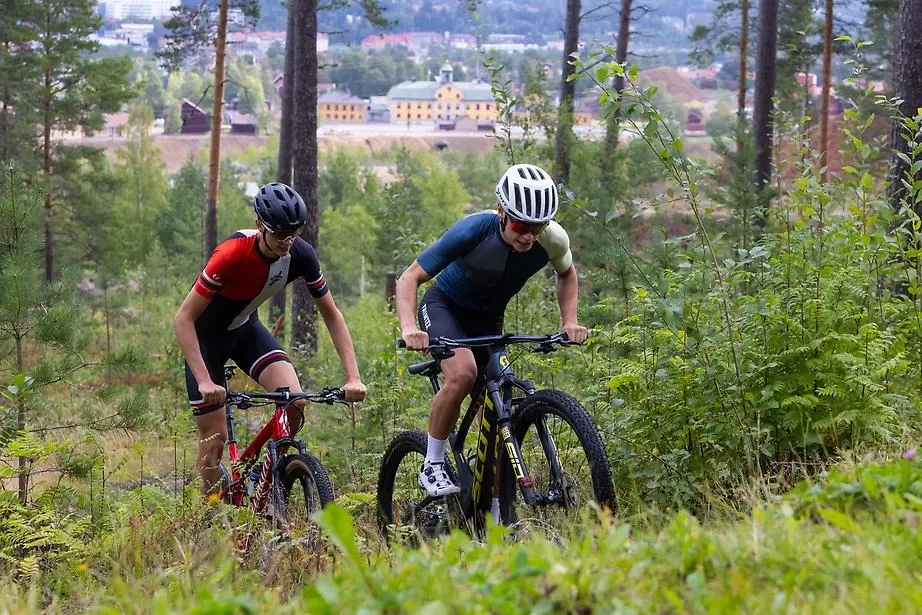 Cyklister på mountainbike cyklar i skogen med Falu gruva i bakgrunden. 