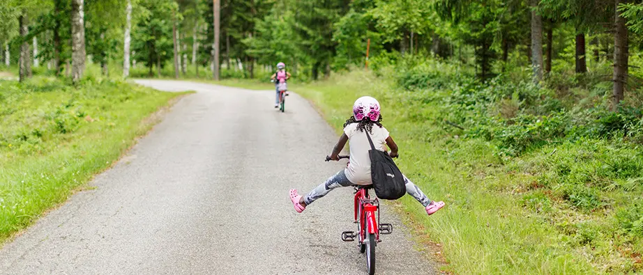 Barn som cyklar på en skogsväg sommartid
