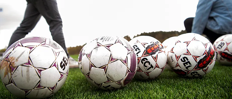 Flera fotbollar som ligger på gräset