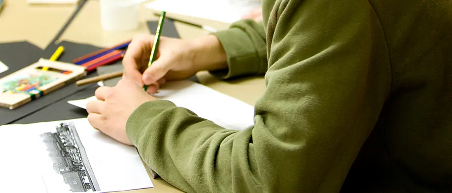 En person som håller i en penna och skriver något på ett papper